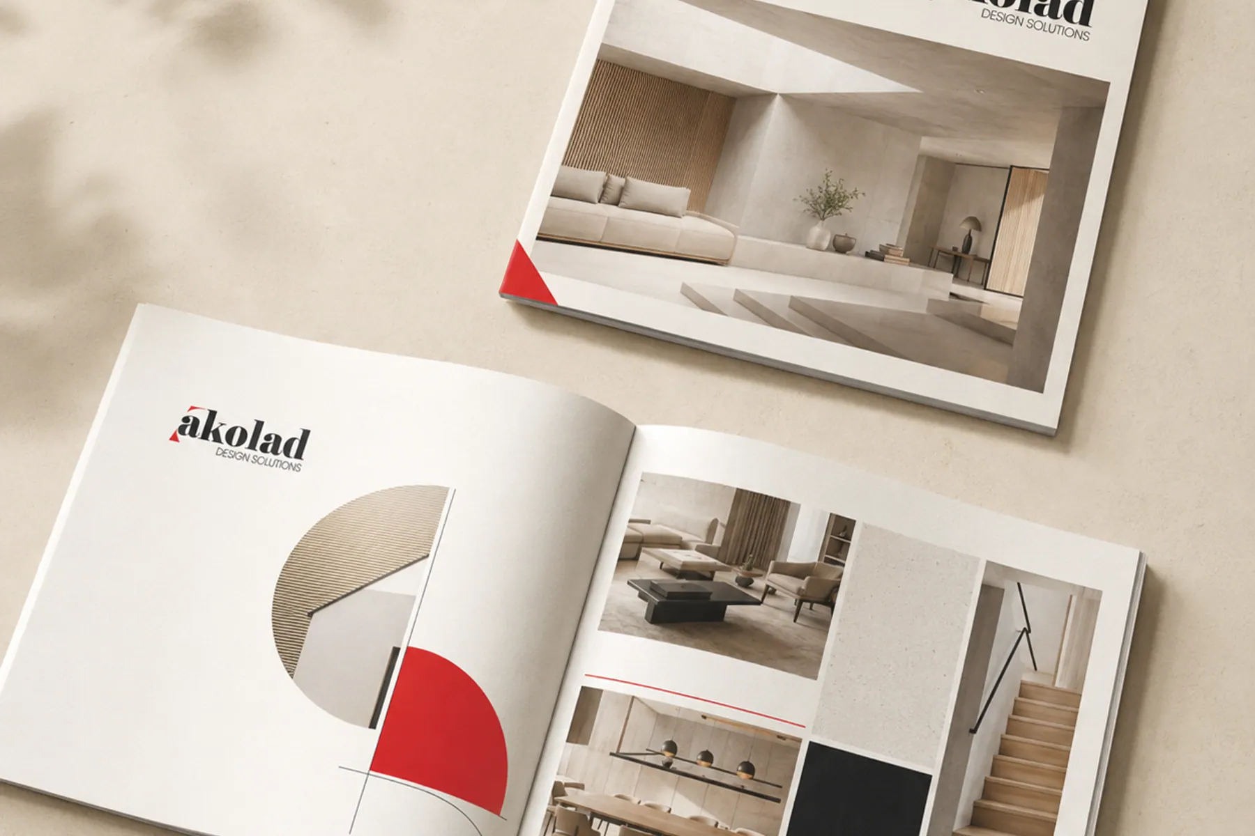 A landscape brochure lying open beside a closed copy, showing an interior photograph on the cover.